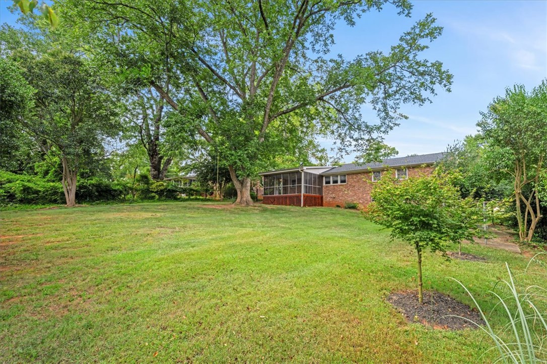 16 State Rd S-23-429 Greenville, SC 29609 - Photo 30 of 34 Mature shade trees frame a sprawling lawn behind this classic brick home.