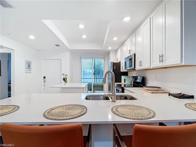 a kitchen with stainless steel appliances granite countertop a stove a sink a dining table and chairs