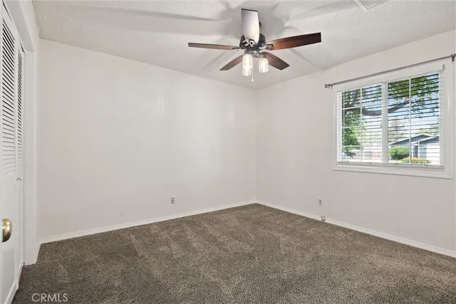 an empty room with a window and a fan
