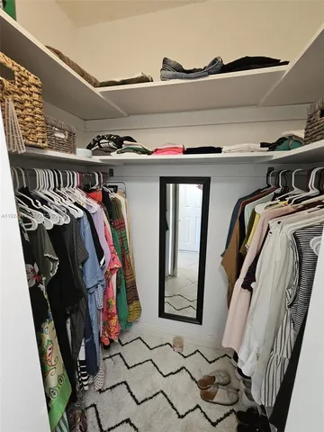 a view of walk in closet with clothes and shoes