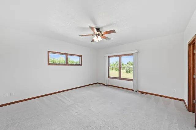 an empty room with a window and a ceiling fan