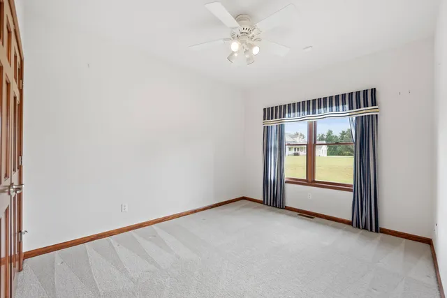 an empty room with chandelier fan and windows