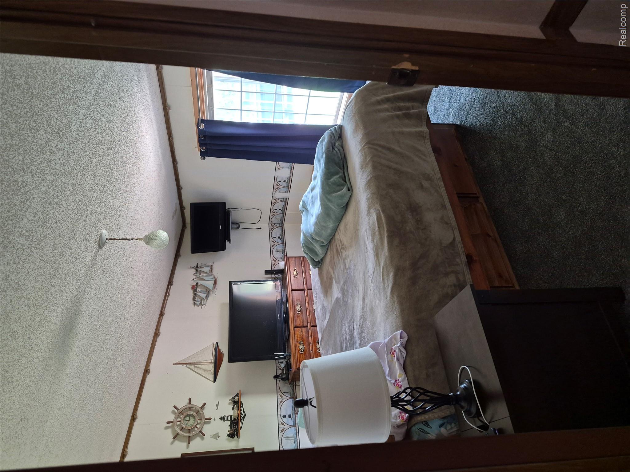 12849 South Delaney Road Perry, MI 48872 - Photo 14 of 34 Carpeted sleeping area featuring a textured ceiling, a window with curtains, and a ceiling-mounted light fixture