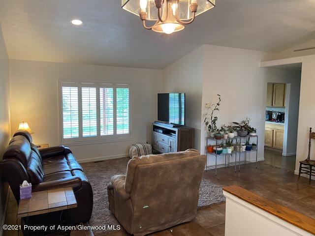1394 Firethorn Drive Rifle, CO 81650 - Photo 15 of 43 a living room with furniture a chandelier and a flat screen tv