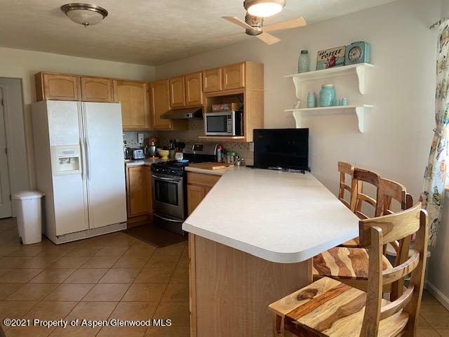 1394 Firethorn Drive Rifle, CO 81650 - Photo 32 of 43 a kitchen with stainless steel appliances granite countertop a refrigerator a stove top oven a sink a dining table and chairs with wooden floor