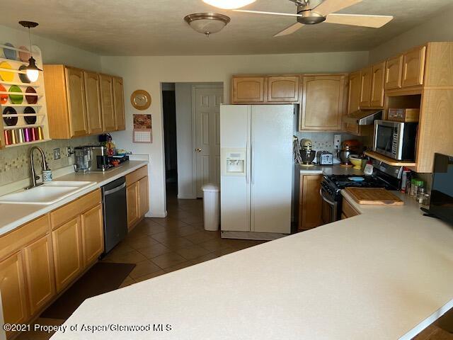 1394 Firethorn Drive Rifle, CO 81650 - Photo 33 of 43 a kitchen with stainless steel appliances a sink a stove a refrigerator cabinets and a window