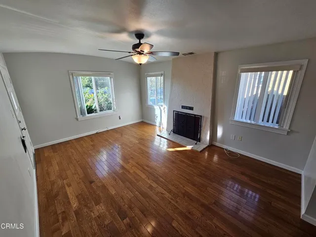 a view of a hallway with wooden floor and a kitchen