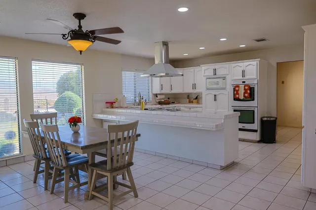 a kitchen with stainless steel appliances kitchen island granite countertop a dining table chairs and a refrigerator