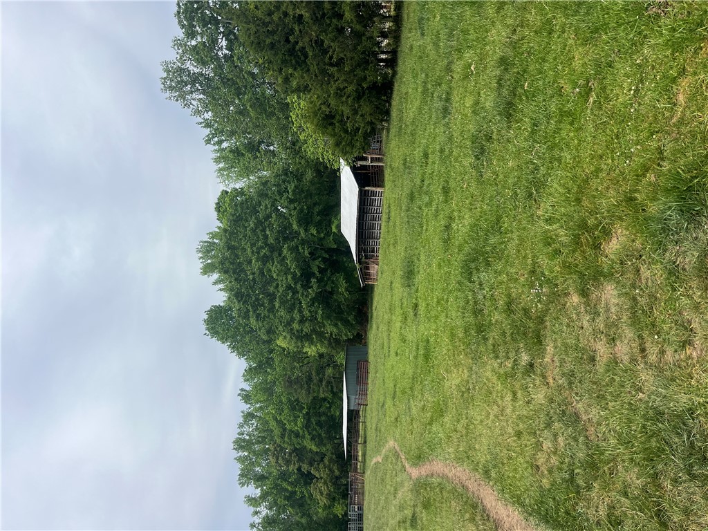 107 Humphrey Wright Road Honea Path, SC 29654 - Photo 12 of 23 Expansive green pasture with a classic barn and mature trees under an open sky.