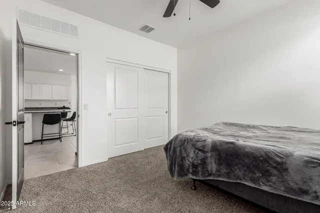 a bed sitting in a bedroom next to a cabinet and a view of kitchen
