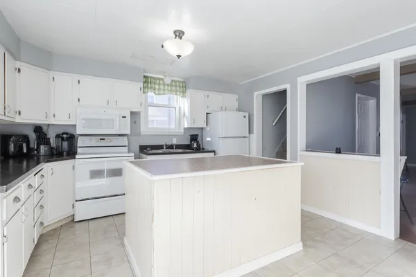 a kitchen with granite countertop a white stove top oven and cabinets