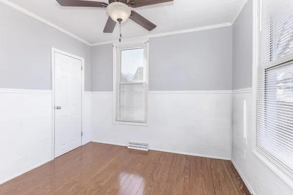 an empty room with wooden floor fan and windows