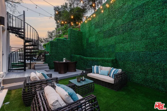 a view of a patio with couches chairs and a fire pit with wooden fence