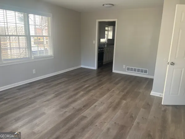 an empty room with wooden floor mirror and windows