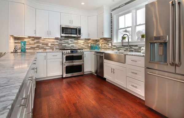 a kitchen with granite countertop wooden floors stainless steel appliances and sink