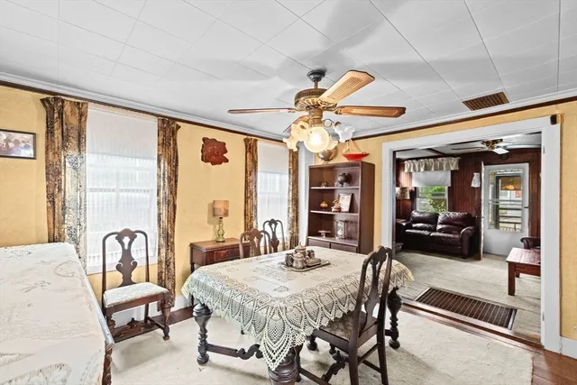 a view of a dining room with furniture a chandelier and large windows