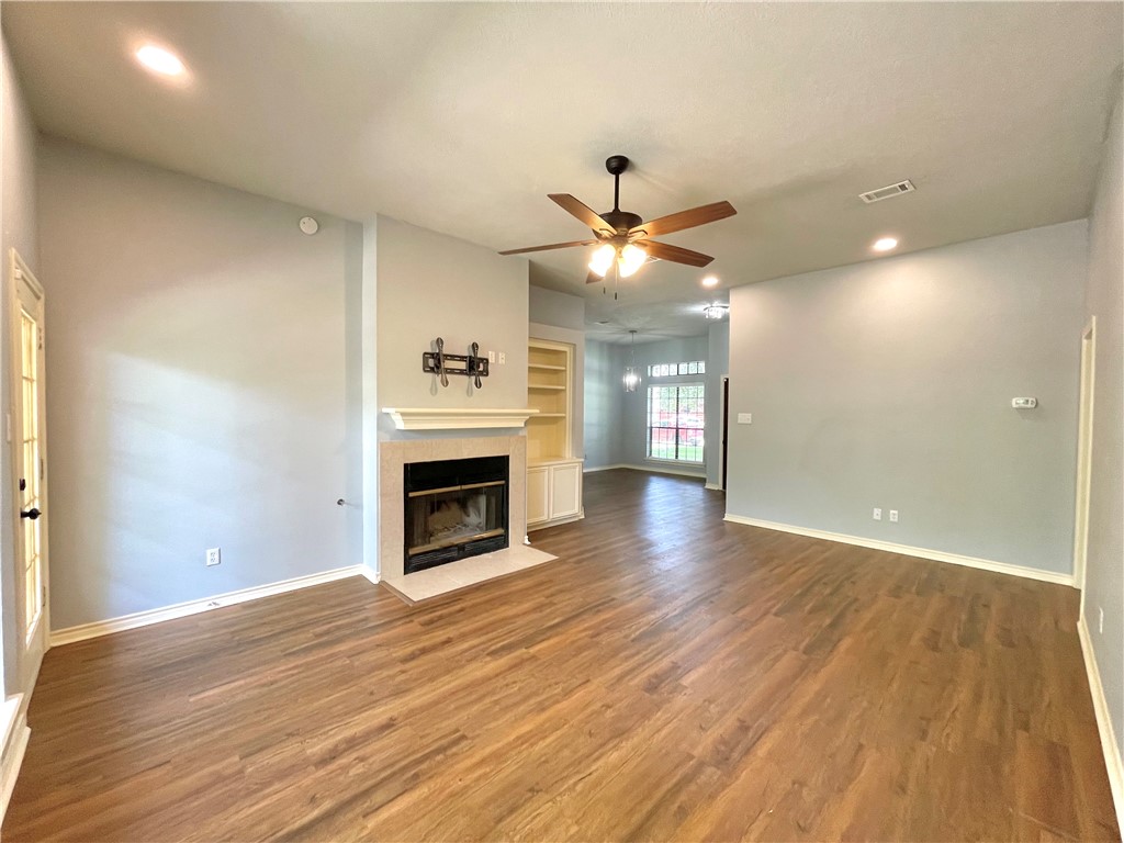 4508 Kensington Road Bryan, TX 77802 - Photo 3 of 25 Unfurnished living room with a tiled fireplace, hardwood / wood-style floors, built in features, and ceiling fan