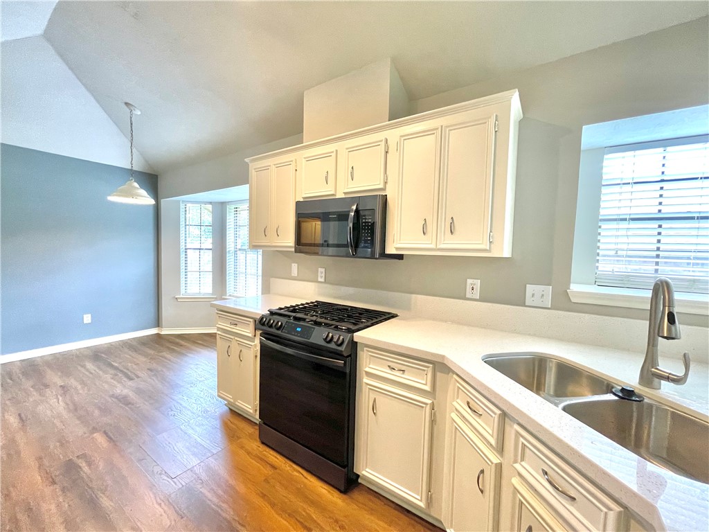 4508 Kensington Road Bryan, TX 77802 - Photo 7 of 25 Kitchen featuring lofted ceiling, sink, gas stove, white cabinetry, and pendant lighting
