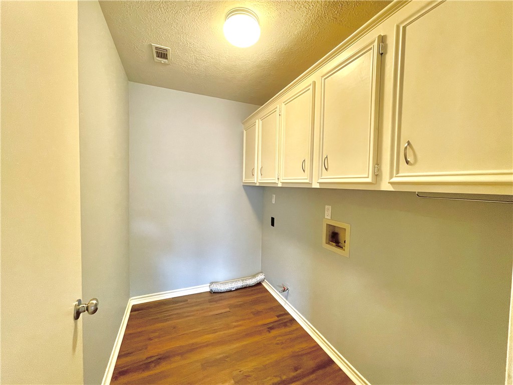 4508 Kensington Road Bryan, TX 77802 - Photo 9 of 25 Laundry room featuring cabinets, washer hookup, dark hardwood / wood-style floors, and a textured ceiling
