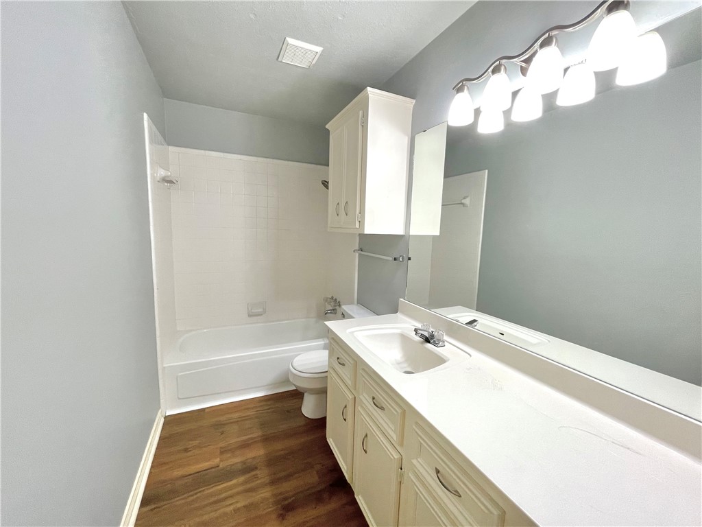 4508 Kensington Road Bryan, TX 77802 - Photo 10 of 25 Full bathroom with tiled shower / bath, wood-type flooring, vanity, and toilet
