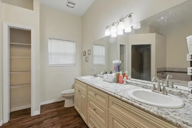 a bathroom with a granite countertop double vanity sink a mirror and a toilet