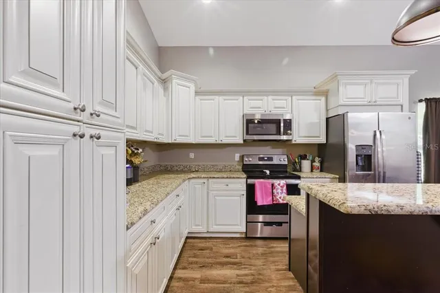 a kitchen with granite countertop a refrigerator stove top oven and sink
