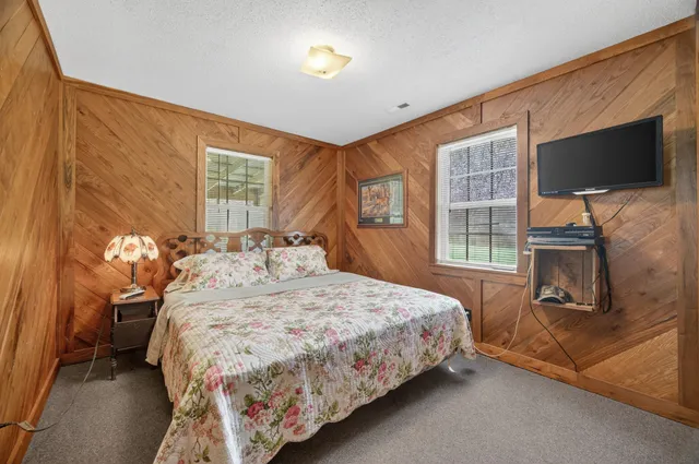a bedroom with a bed television on desk and a window