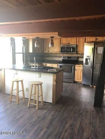 a kitchen with stainless steel appliances granite countertop a table chairs stove and wooden floor