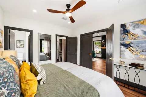 a bedroom with a bed ceiling fan and a wooden floor