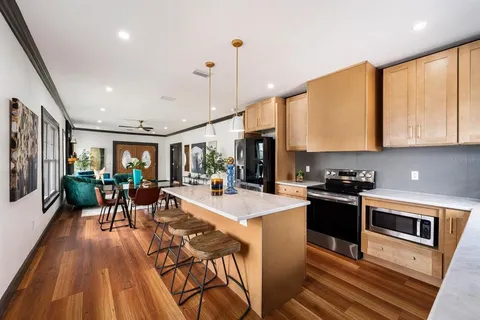 a kitchen with stainless steel appliances granite countertop a stove top oven a sink dishwasher a dining table and chairs with wooden floor