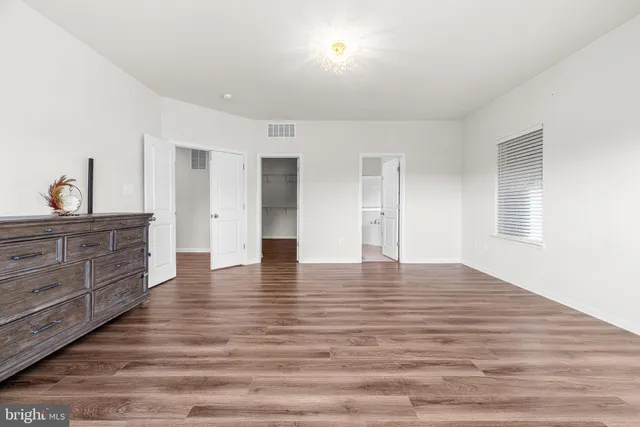 a view of an empty room with wooden floor and cabinet