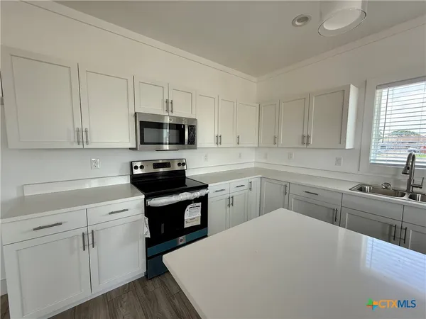 a kitchen with sink a microwave and cabinets
