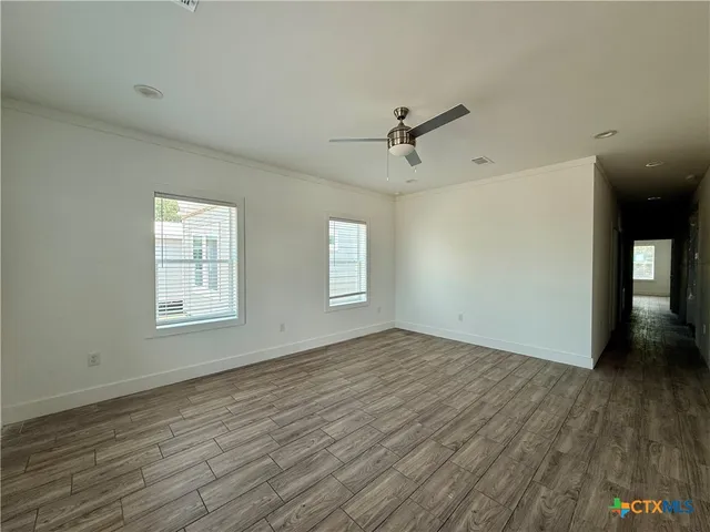 a view of empty room with wooden floor and fan