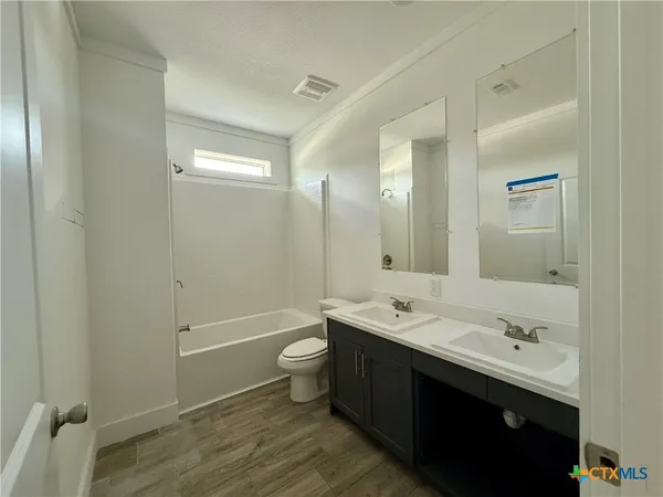 a bathroom with a double vanity sink toilet mirror and bathtub