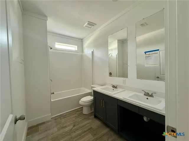 a bathroom with a double vanity sink toilet mirror and bathtub