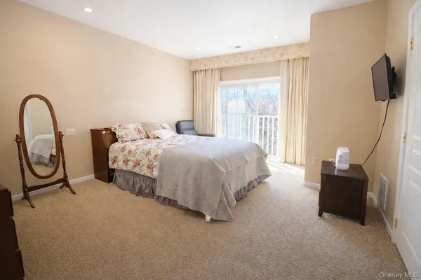 a bed sitting in a bedroom next to a window with a flat screen tv and dresser