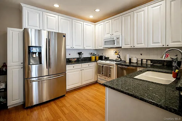 a kitchen with granite countertop a refrigerator sink and cabinets