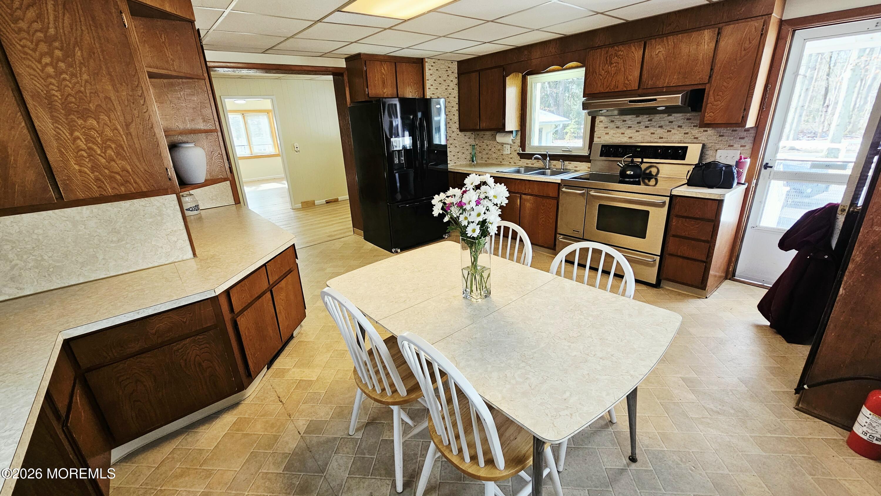 12 Anderson Drive Howell, NJ 07731 - Photo 3 of 26 a kitchen with stainless steel appliances a stove a refrigerator a sink a dining table and chairs