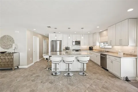 a large kitchen with kitchen island a large counter space a sink stainless steel appliances and cabinets