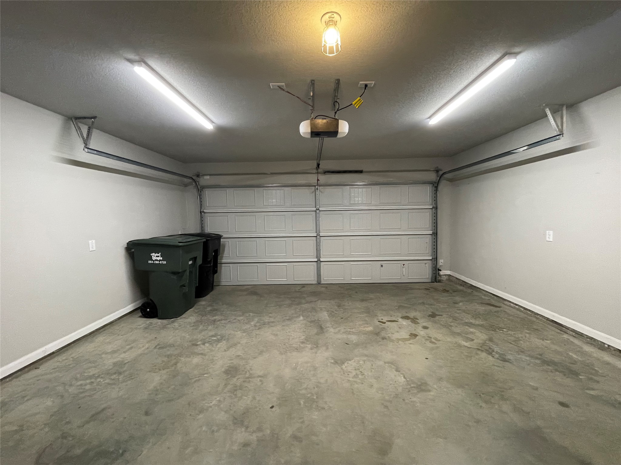 8113 Northgate Loop Temple, TX 76502 - Photo 32 of 35 Two-car garage featuring a paneled door, concrete flooring, and ceiling-mounted linear lighting