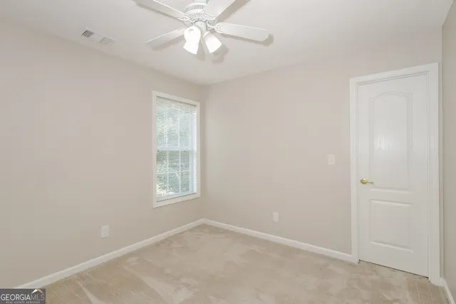 an empty room with windows and fan