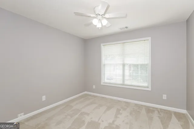 an empty room with windows and ceiling fan