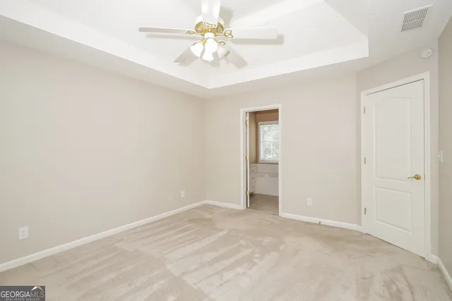 a view of a room with a ceiling fan and carpet