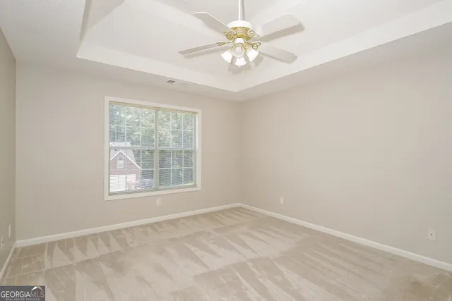 an empty room with chandelier fan and windows