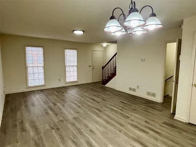 an empty room with wooden floor and chandelier