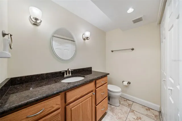a bathroom with a granite countertop sink a toilet and a mirror