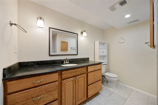 a bathroom with a granite countertop sink a toilet and shower