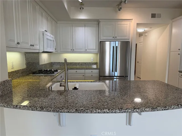 a kitchen with stainless steel appliances granite countertop a sink refrigerator and cabinets