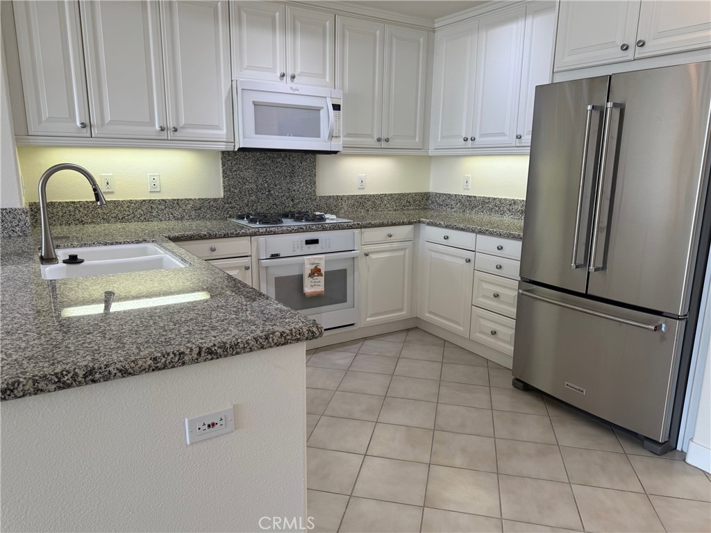 1400 East Ocean Boulevard, Unit 1203 Long Beach, CA 90802 - Photo 9 of 34 a kitchen with granite countertop a refrigerator sink and cabinets
