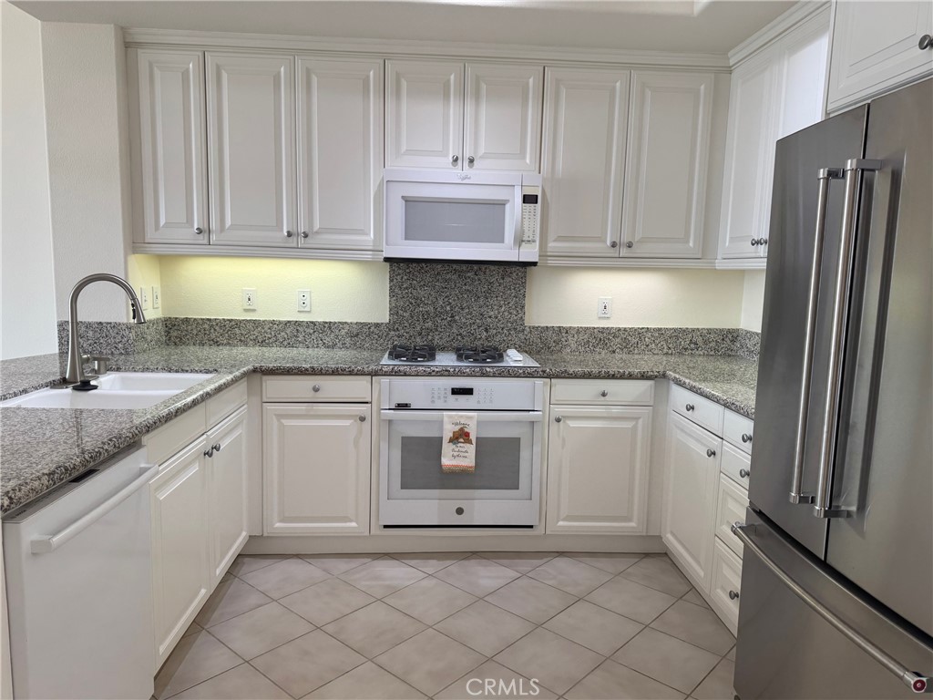 1400 East Ocean Boulevard, Unit 1203 Long Beach, CA 90802 - Photo 10 of 34 a kitchen with granite countertop white cabinets and stainless steel appliances